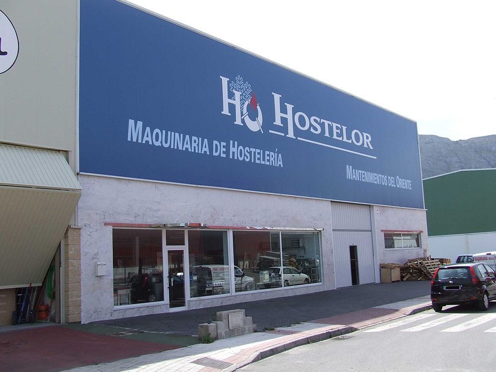 Nave de Hostelor con rótulo azul y aparcamiento