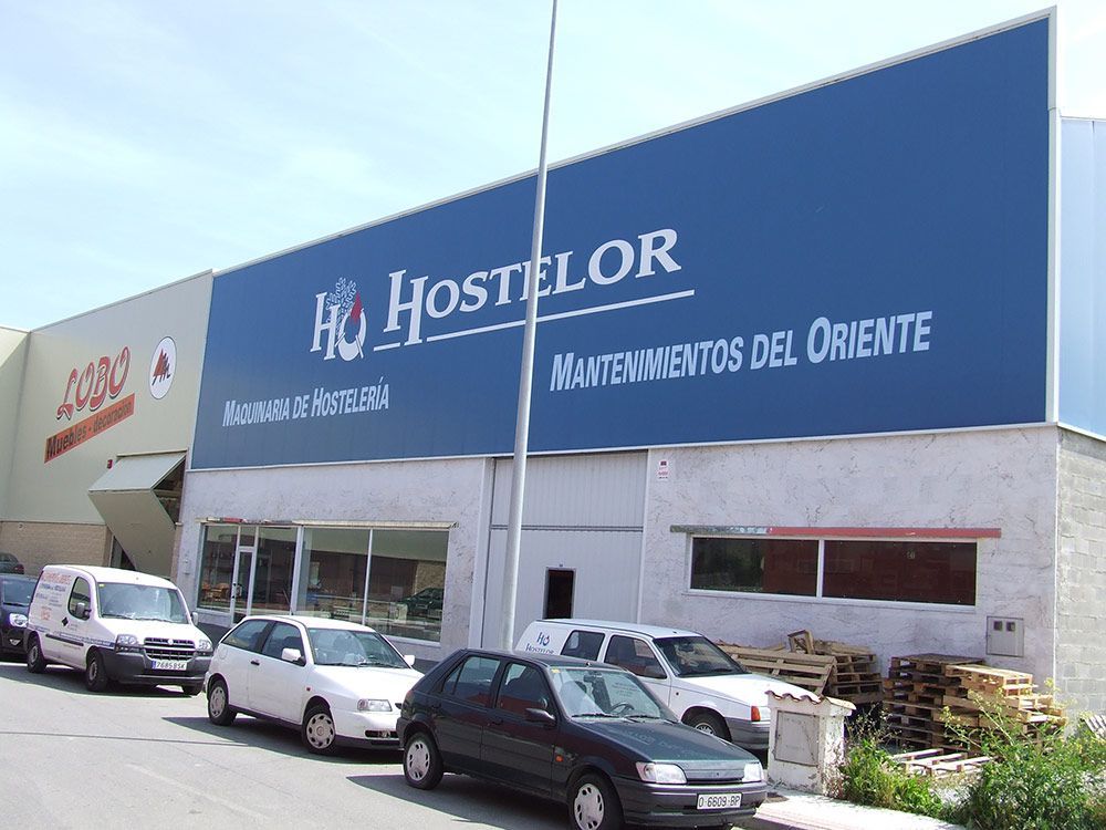 Nave de Hostelor con rótulo azul y aparcamiento