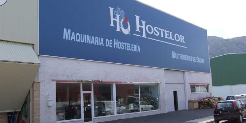 Nave de Hostelor con rótulo azul y aparcamiento